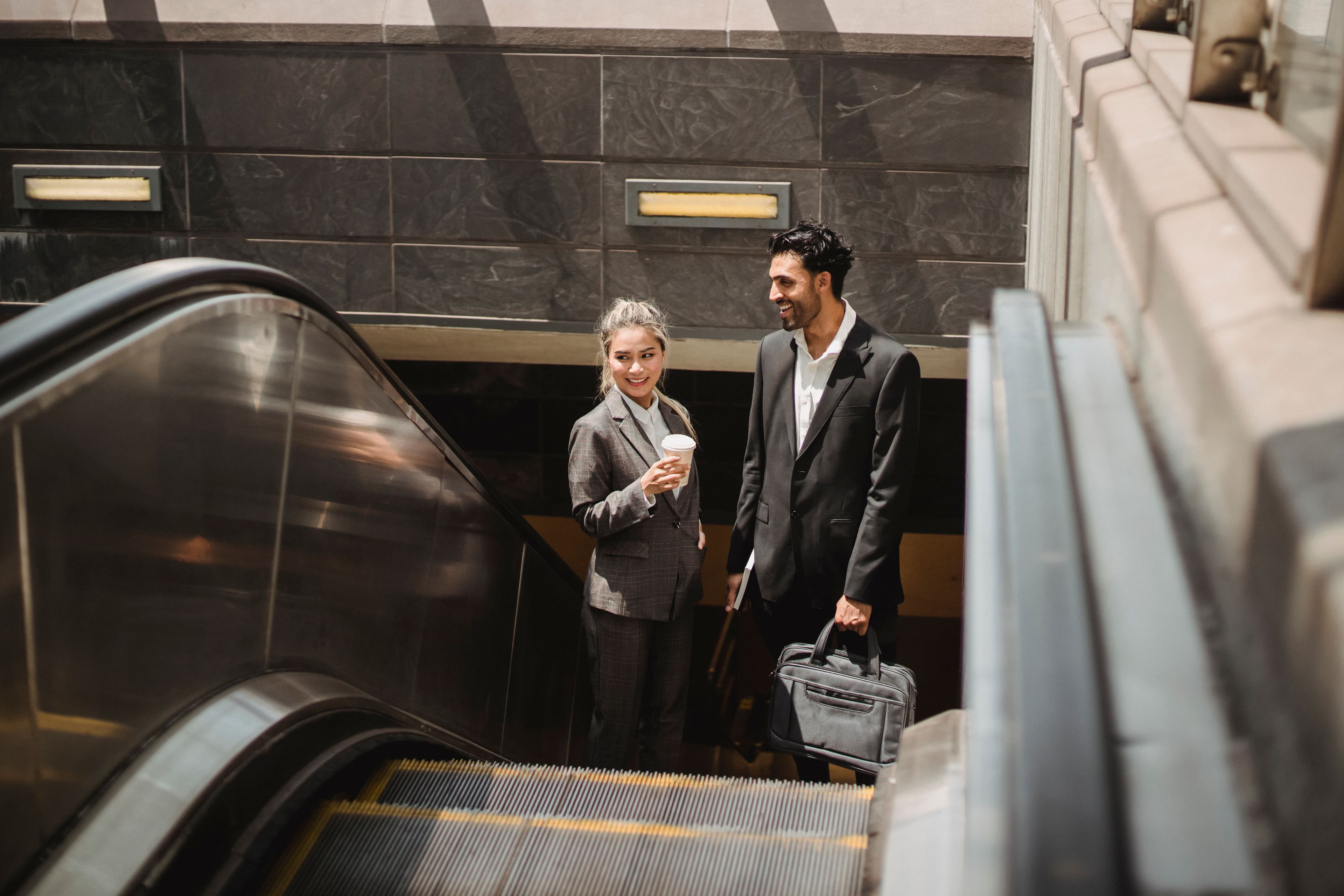 Two professionals travelling up an escalator