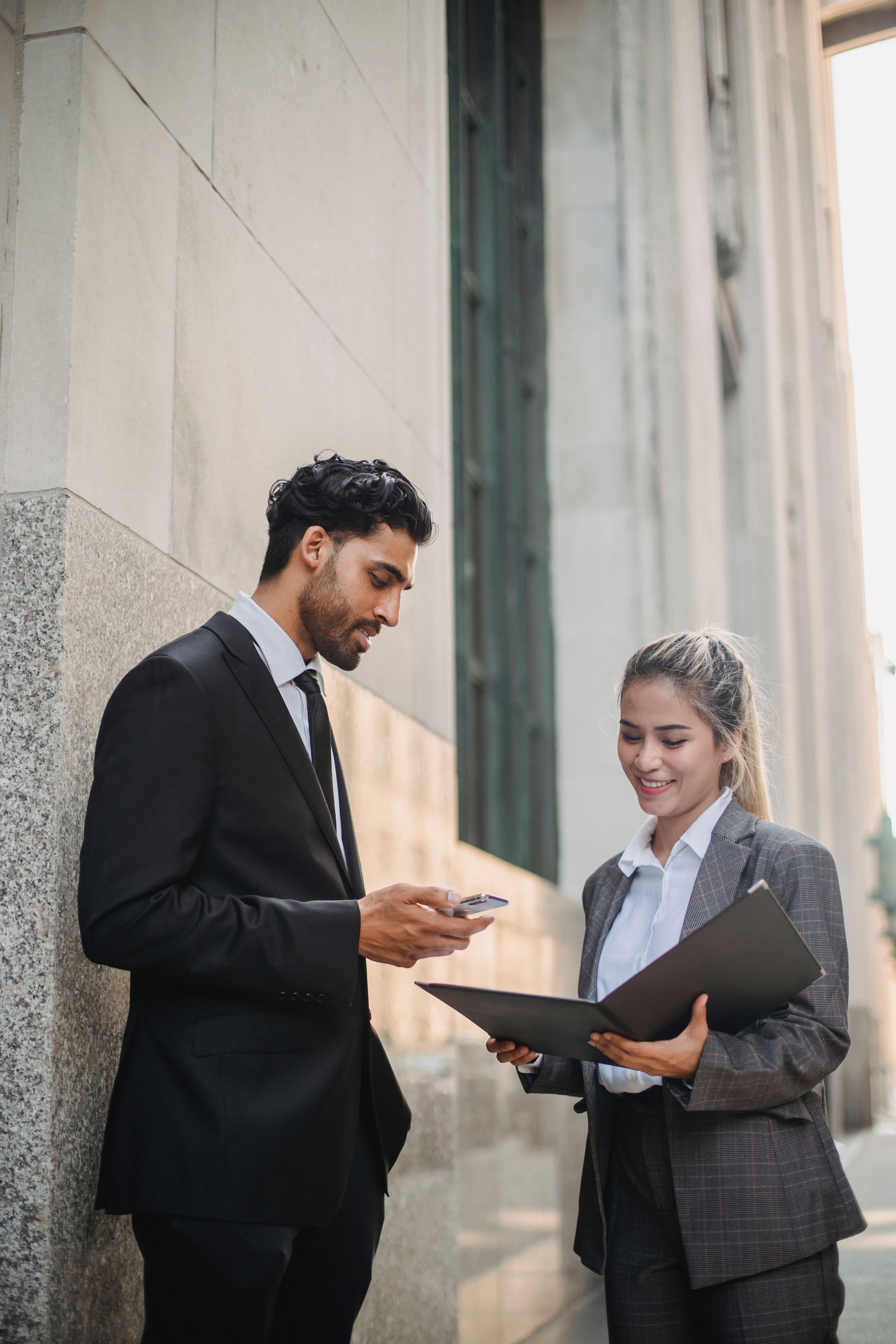 Two professionals reviewing an open folder outside an office building